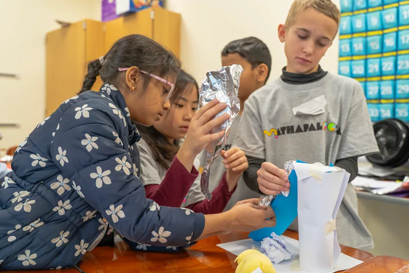 Children in a North Carolina school district work collaboratively on a project. The district has a plan to reduce its magnet themes