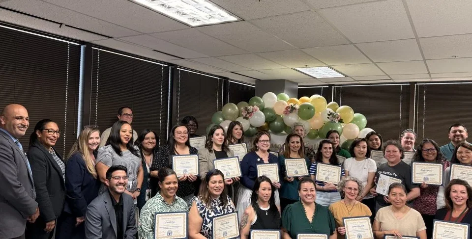 a group of Montessori training graduates pose for a picture while holding their certificates